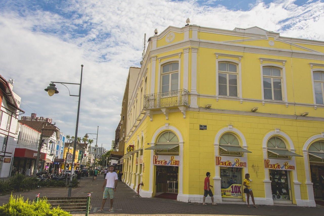 Casarão amarelo em estilo eclético na esquina da rua de pedestres do centro de Joinville, Santa Catarina, sob céu com nuvens